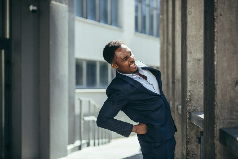 Man in suit stretching outside.